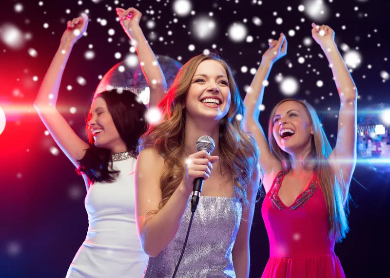 Tre donne cantano e ballano il karaoke a una festa aziendale